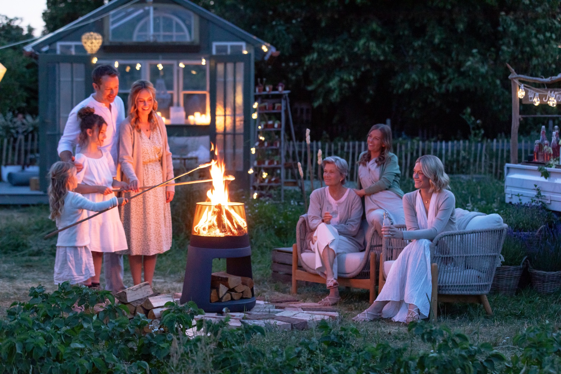 Familie am Feuerkorb in der Abenddämmerung